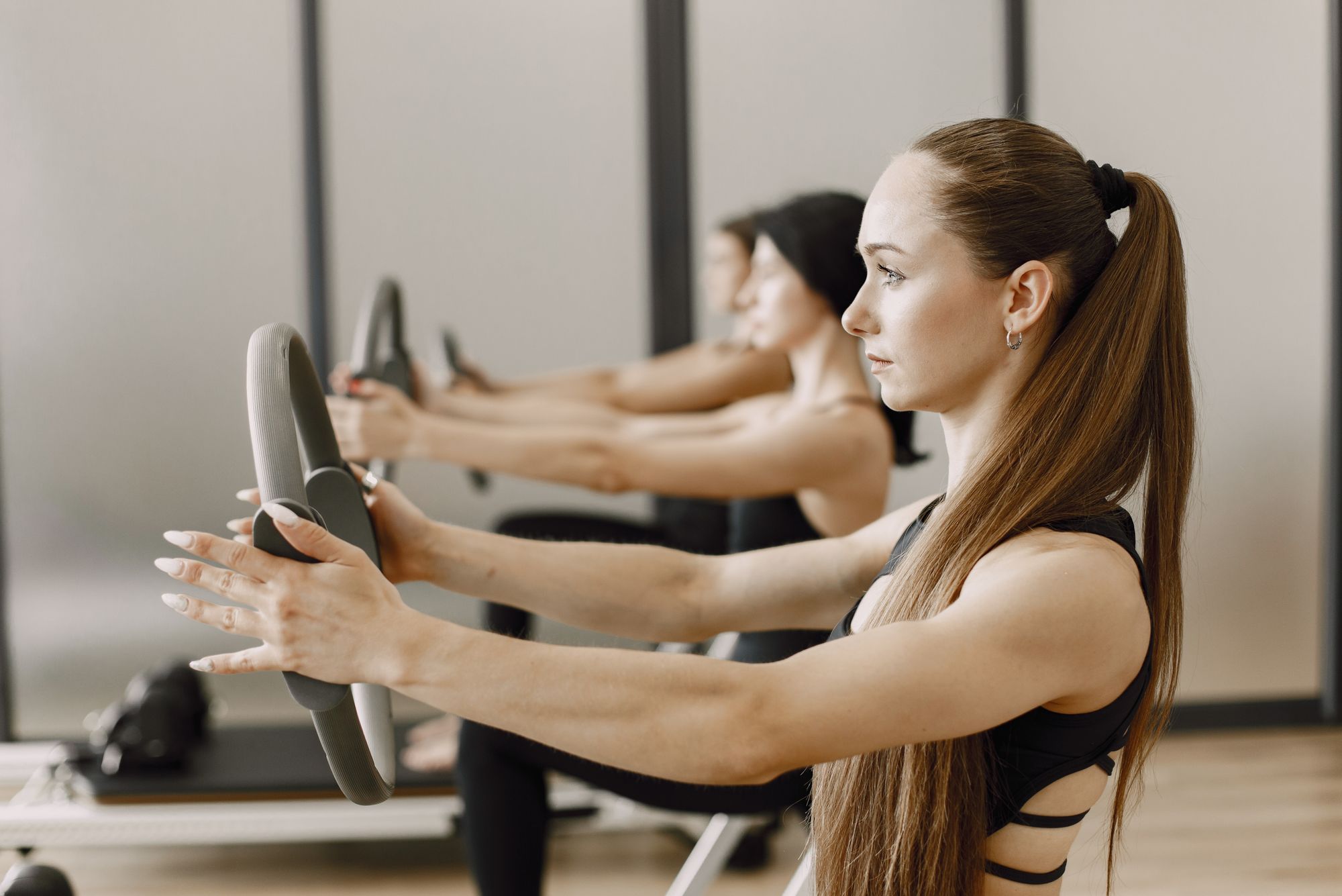 Pilates-óra: csoport gyűrűvel gyakorol egy világos teremben